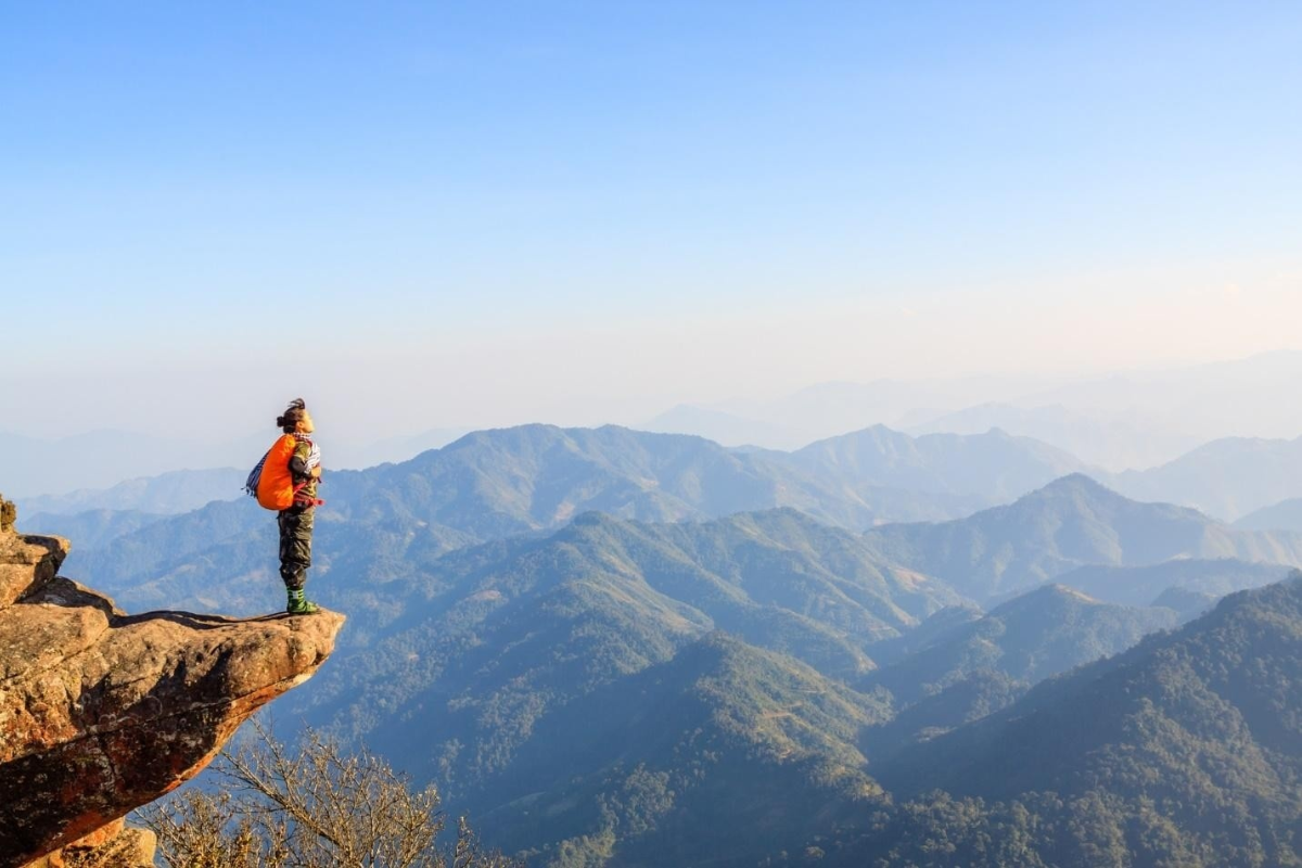 Traveler standing on the iconic cliff rock at Pha Luong Peak surrounded by white clouds